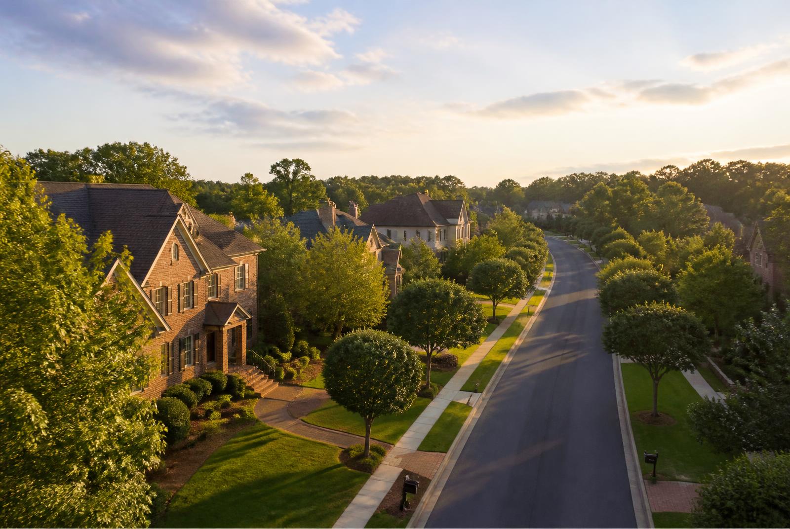 Golden-hour view down a street of brick and stone custom estate homes in the Waxhaw and Weddington luxury corridor of Union County, NC
