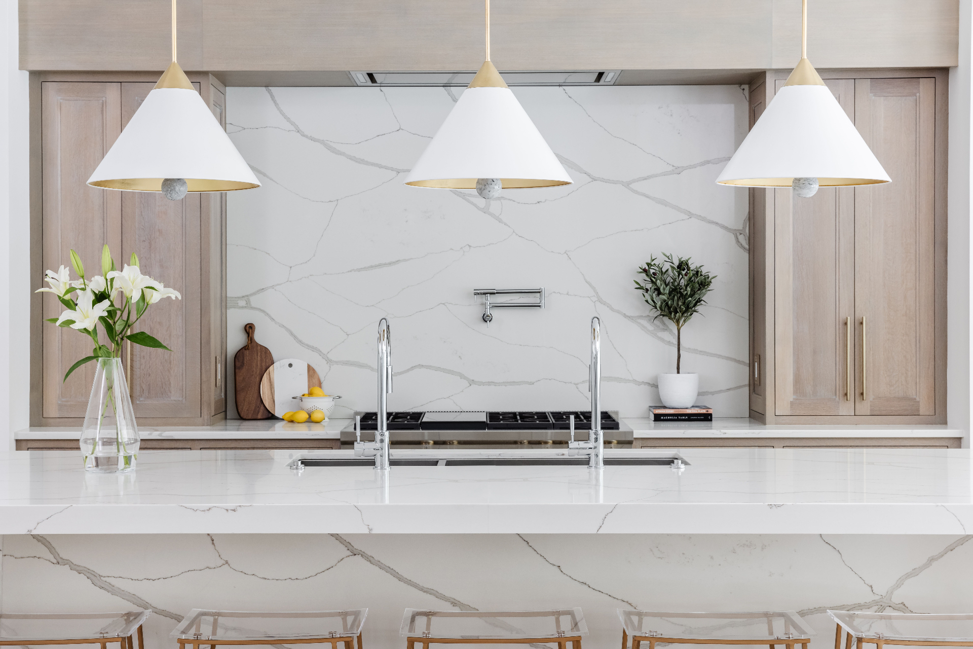 Highgate estate chef kitchen — Calacatta quartz island and backsplash, rift white-oak cabinetry, professional cooktop with pot-filler, and white cone pendants